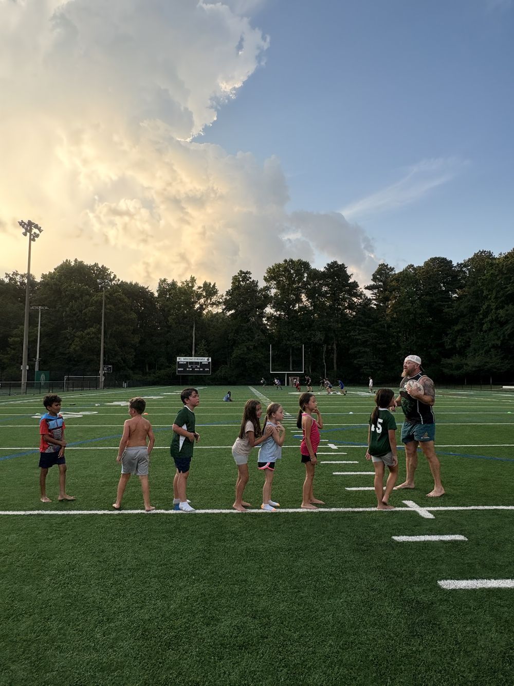 Kids lined up at Touch Tuesdays under a big evening sky